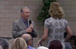 A woman walks out of Michigan Republican Rep. Tim Walberg's lie-filled town hall