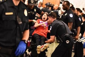 A disabled woman is carried out of the hearing room by police after protesting the Graham-Cassidy bill
