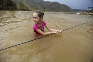 Ruby Rodriguez, 8, looks back at her mother as she wades across the San Lorenzo Morovis river with her family, since the bridge was swept away by Hurricane Maria
