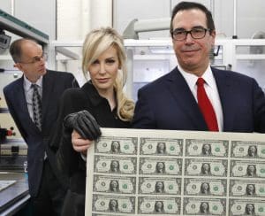 Treasury Secretary Steven Mnuchin, right, and his wife Louise Linton, hold up a sheet of new $1 bills