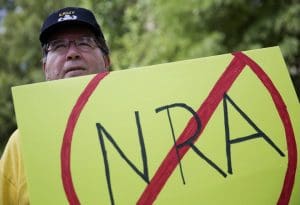 U.S. Army veteran Pax Riddle holds a sign during a rally protesting the National Rifle Association's annual convention
