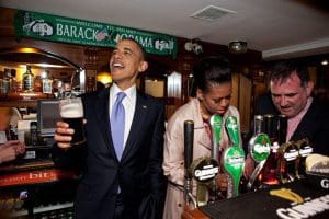President Barack Obama talks with pub-goers as First Lady Michelle Obama draws a pint at Ollie Hayes pub in Moneygall, Ireland, May 23, 2011. (Official White House Photo by Pete Souza) This official White House photograph is being made available only for publication by news organizations and/or for personal use printing by the subject(s) of the photograph. The photograph may not be manipulated in any way and may not be used in commercial or political materials, advertisements, emails, products, promotions that in any way suggests approval or endorsement of the President, the First Family, or the White House.