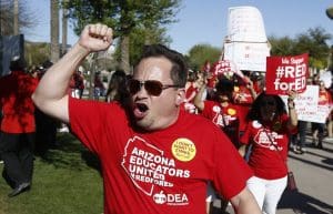 Arizona teachers and education advocates shout as they march at the Arizona Capitol highlighting low teacher pay and school funding