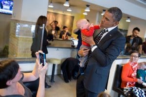 President Barack Obama holds a baby while greeting patrons at The Coupe restaurant in Washington, D.C.