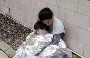 Immigrant mother and child sleeping on the ground at a McAllen, Texas border patrol station