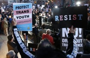 A participant holds signs up during a rally next door to the Stonewall National Monument on Thursday, Feb. 23, 2017, in New York.