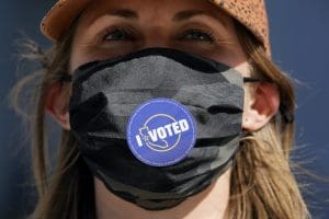 Woman in mask with I Voted sticker