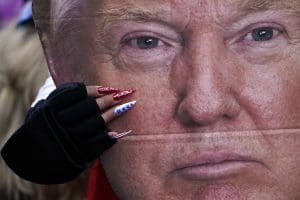 A woman holds a cutout of President Donald Trump's face.