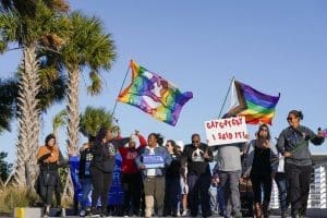 Marchers wave flags as they walk at the St. Pete Pier during a rally and march to protest against a bill dubbed by opponents as the 