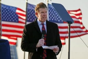 Matt Birk reading an invocation at a Rochester, Minnesota campaign rally for Donald Trump in 2020 in front of three American flags