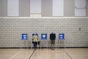 Two voters cast primary ballots alongside three blue empty voter booths at Zion Lutheran Church in Anoka, Minnesota on Tuesday, Aug. 9, 2022.