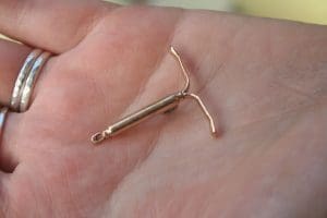 A hand holding a bronze cast of an IUD