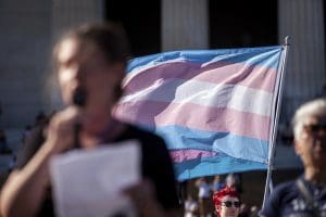 A trans pride flag is displayed behind a speaker at an anti-trans event at the Lincoln Memorial in Washington, D.C.