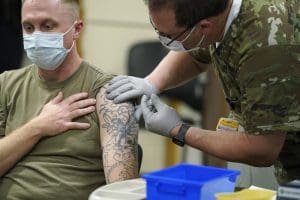 Staff Sgt. Travis Snyder, left, receives the first dose of the Pfizer COVID-19 vaccine given at Madigan Army Medical Center at Joint Base Lewis-McChord in Washington state, Dec. 16, 2020, south of Seattle.