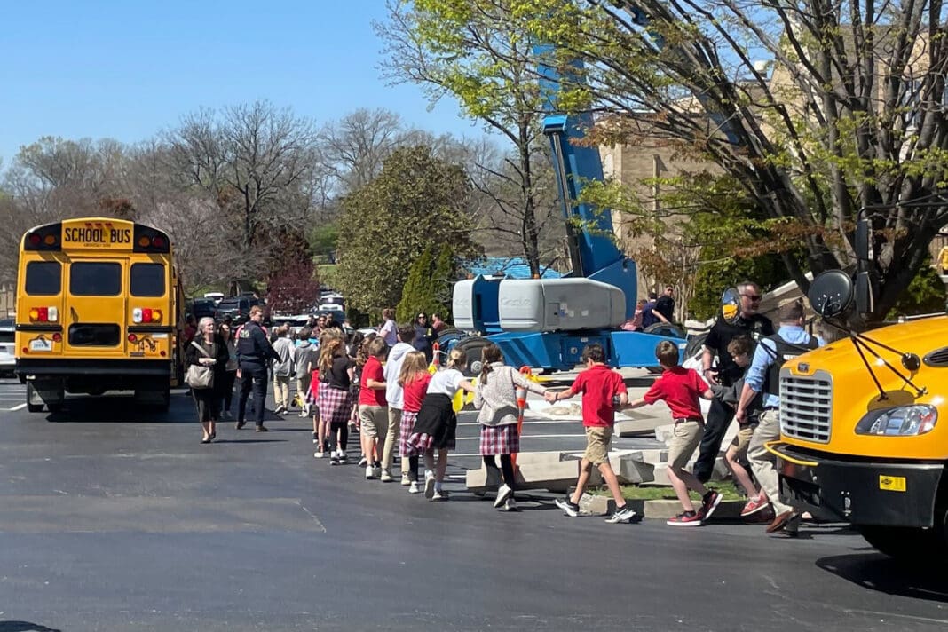 Children from The Covenant School hold hands as they are taken to a reunification site after a shooting at their school in Nashville, Tennessee, on Monday March, 27, 2023.