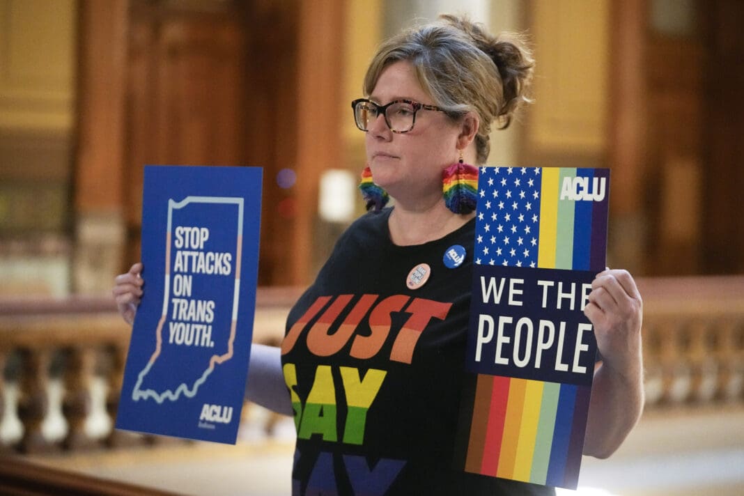 Kristen Cooper holds signs protesting anti-LGBTQ legislation outside of the Senate chamber at the Indiana Statehouse on Feb. 22, 2023, in Indianapolis.