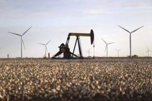 A pump jack and wind turbines stand inside of a cotton field on Oct. 18, 2015, near Lamesa, Texas. The U.S. government is greenlighting a proposed multibillion-dollar transmission line Thursday, May 18, 2023, that would send primarily wind-generated electricity from the rural plains of New Mexico to big cities in the West.