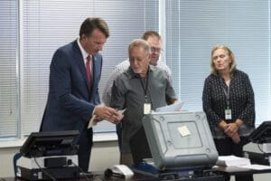 Virginia Gov. Glenn Youngkin is shown a voter receipt slip while touring the Loudoun County County Office of Elections, in Leesburg, Va., Sept. 20, 2022.