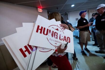 A woman carries yard signs for Hung Cao, Republican candidate for Virginia's 10th Congressional district, at the Prince William County Republican Committee's election kickoff barbecue at VFW Post 1503 in Dale City, Va., on Saturday, September 17, 2022.